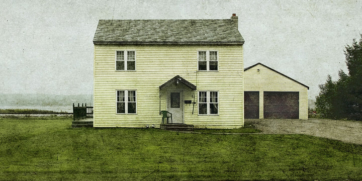 A cream-colored two-story farmhouse with a garage sits on green grass under an overcast sky.