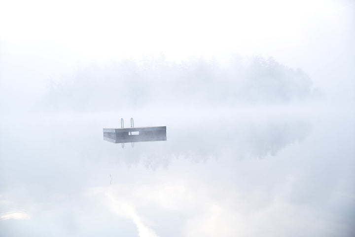 A rectangular structure with two vertical poles floats suspended among white and gray clouds.