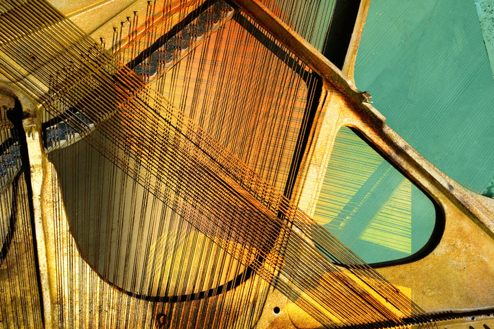 Abstract artwork featuring piano strings and keys in gold, orange, and turquoise tones arranged in geometric composition.