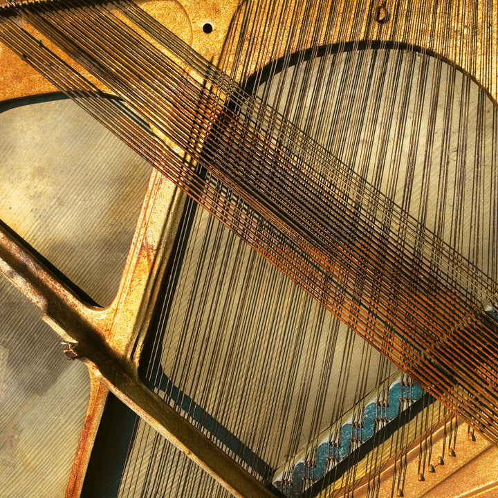 Abstract artwork featuring piano strings and keys in gold, brown, white, and blue tones with linear composition.