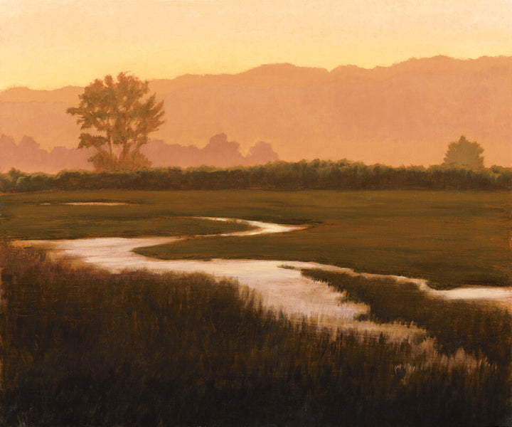A winding river cuts through marshland with trees silhouetted against a golden-orange hazy sky and distant mountains.