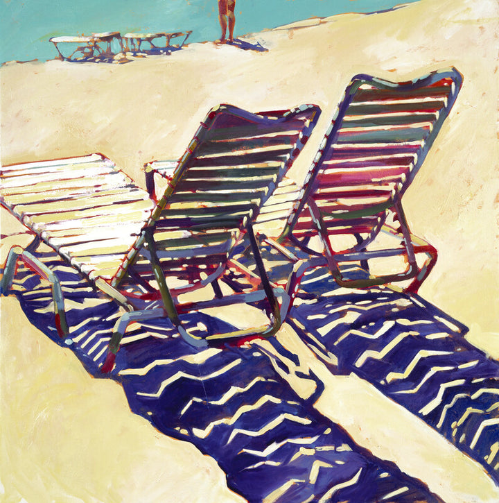 Two striped beach chairs cast long shadows on sand, with boats and a figure visible in the background under a blue sky.
