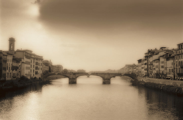 Sepia-toned photograph of Florence's Arno River with a multi-arched bridge, Renaissance buildings, and misty atmosphere.