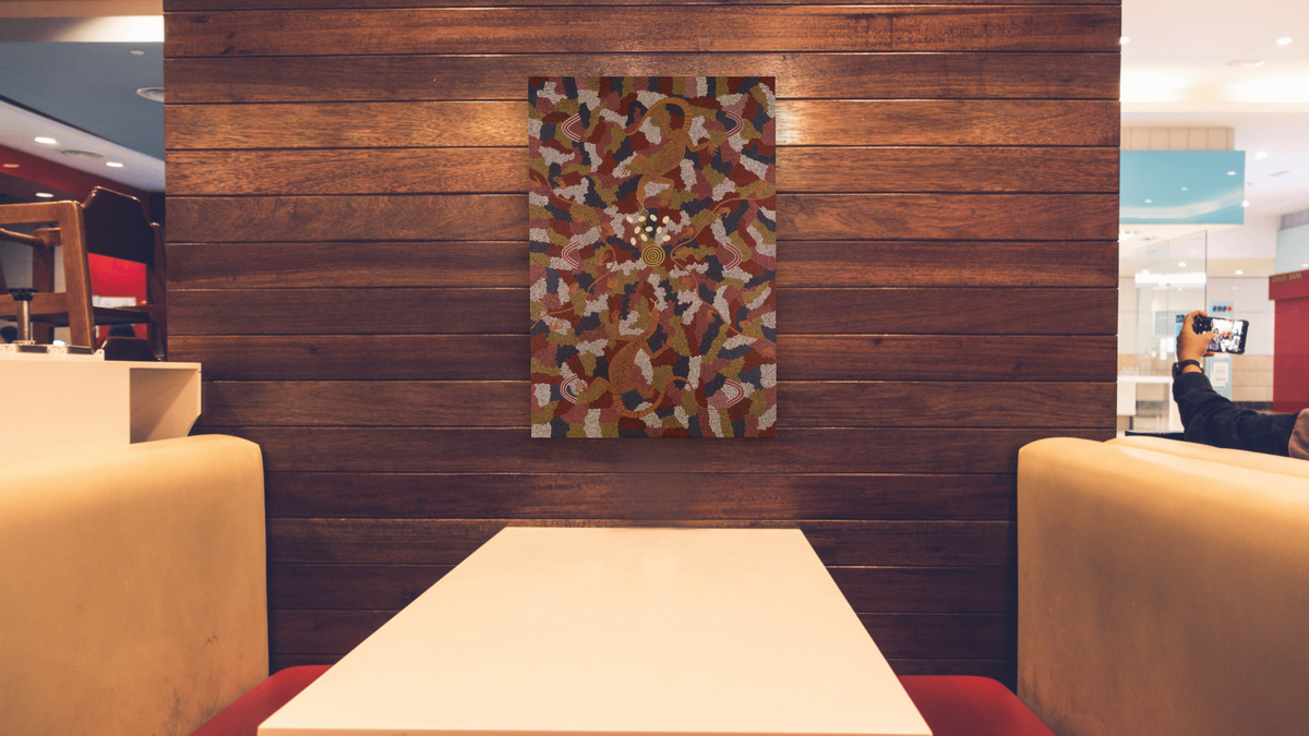 Goanna Dreaming by Clifford Possum Tjapaltjarri, shown at 28 × 42 in (71.1 × 106.7 cm) as gallery-wrapped canvas, restaurant