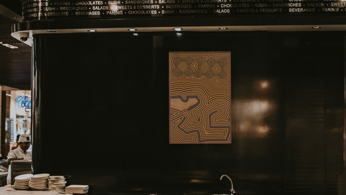 Marpurinya by Ronnie Tjampitjinpa, shown at 28 × 42 in (71.1 × 106.7 cm) on canvas in Arber Warm Walnut, restaurant