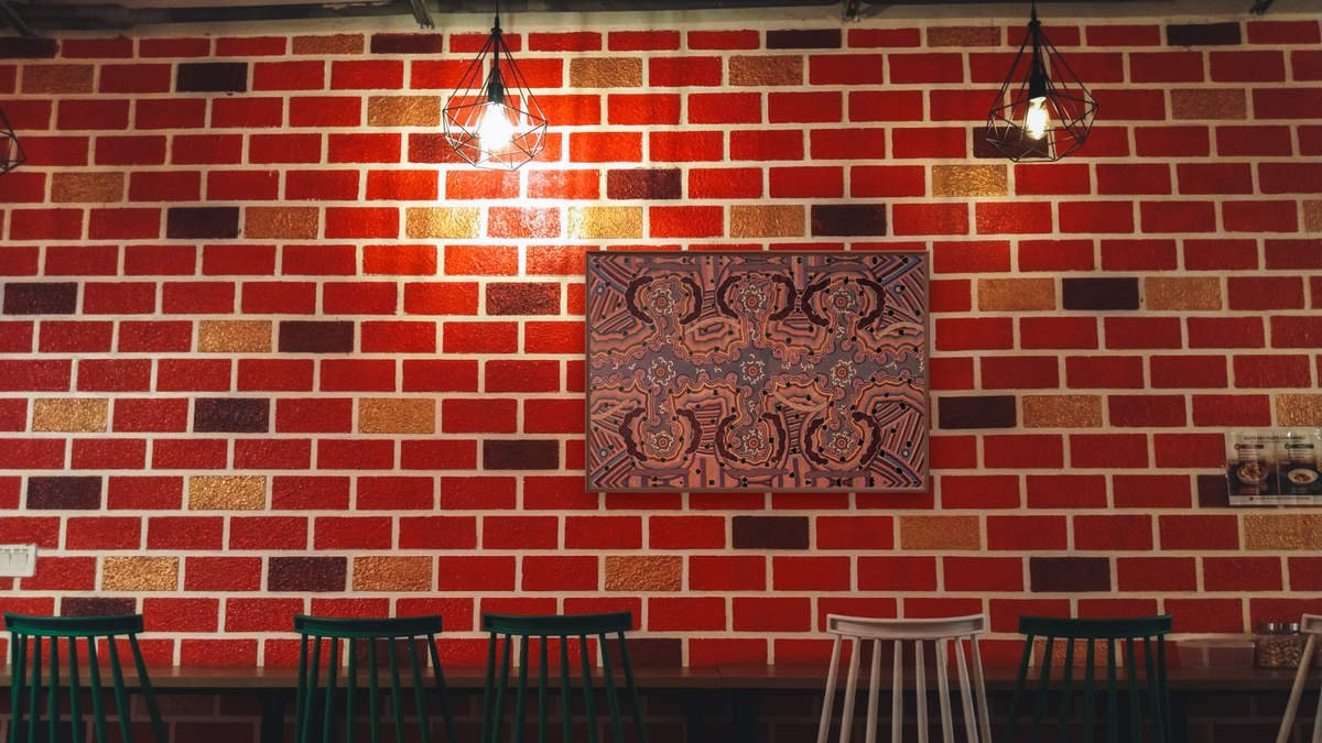 Yuelamu honey ant dreaming by Clifford Possum Tjapaltjarri, shown at 28 × 42 in (71.1 × 106.7 cm) on canvas in Arber Warm Walnut, restaurant