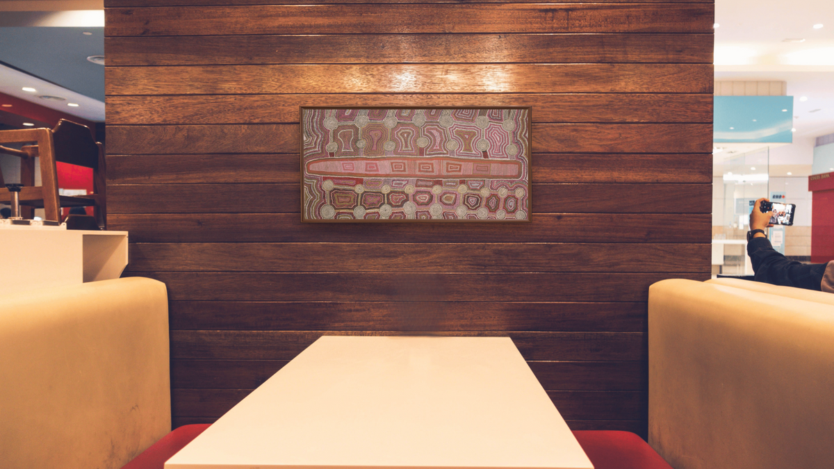 Tingari Dreaming by Timmy Payungka Tjapangati, shown at 20 × 40 in (50.8 × 101.6 cm) on canvas in Arber Warm Walnut, restaurant
