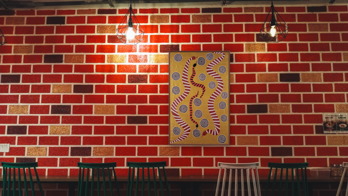 Snake Dreaming by Billy Stockman Tjapaltjarri, shown at 28 × 42 in (71.1 × 106.7 cm) on canvas in Arber Warm Walnut, restaurant